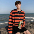 Young man wearing oversized red and black striped telnyashka long sleeve shirt by the sea